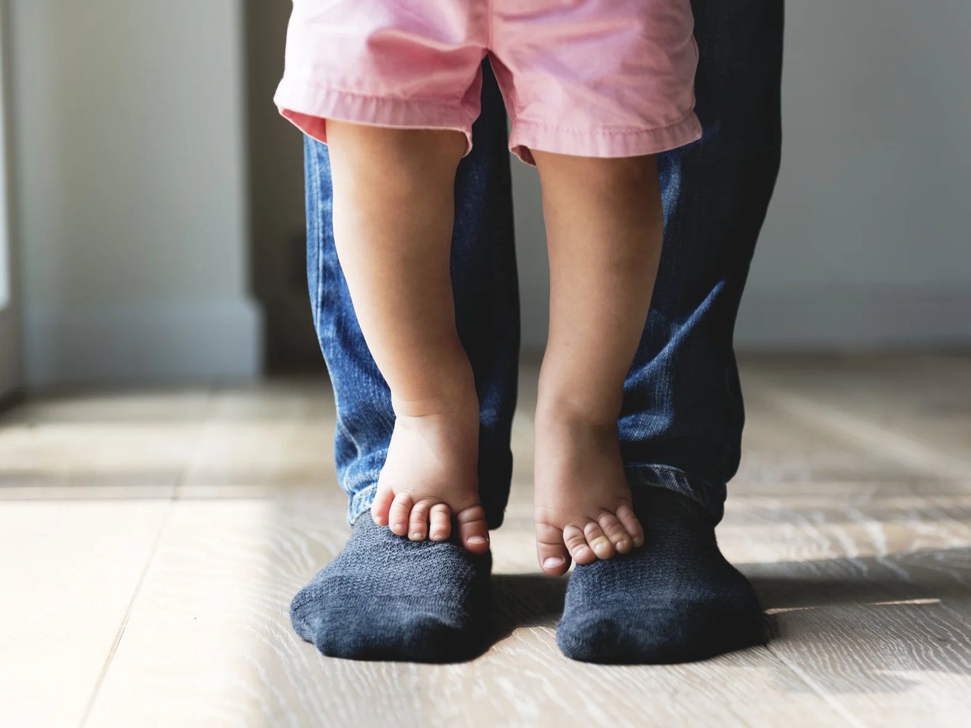Un enfant debout sur les pieds d’un parent, en chaussettes